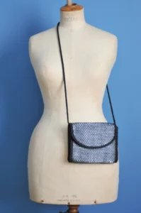 mannequin de couture portant un sac à main vintage de petit format et plat en cellulose noir et gris tressé style pochette vintage années 80