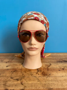 tete de mannequin portant un foulard en soie vintage et des lunettes de soleil vintage en métal rouge et de forme aviateur