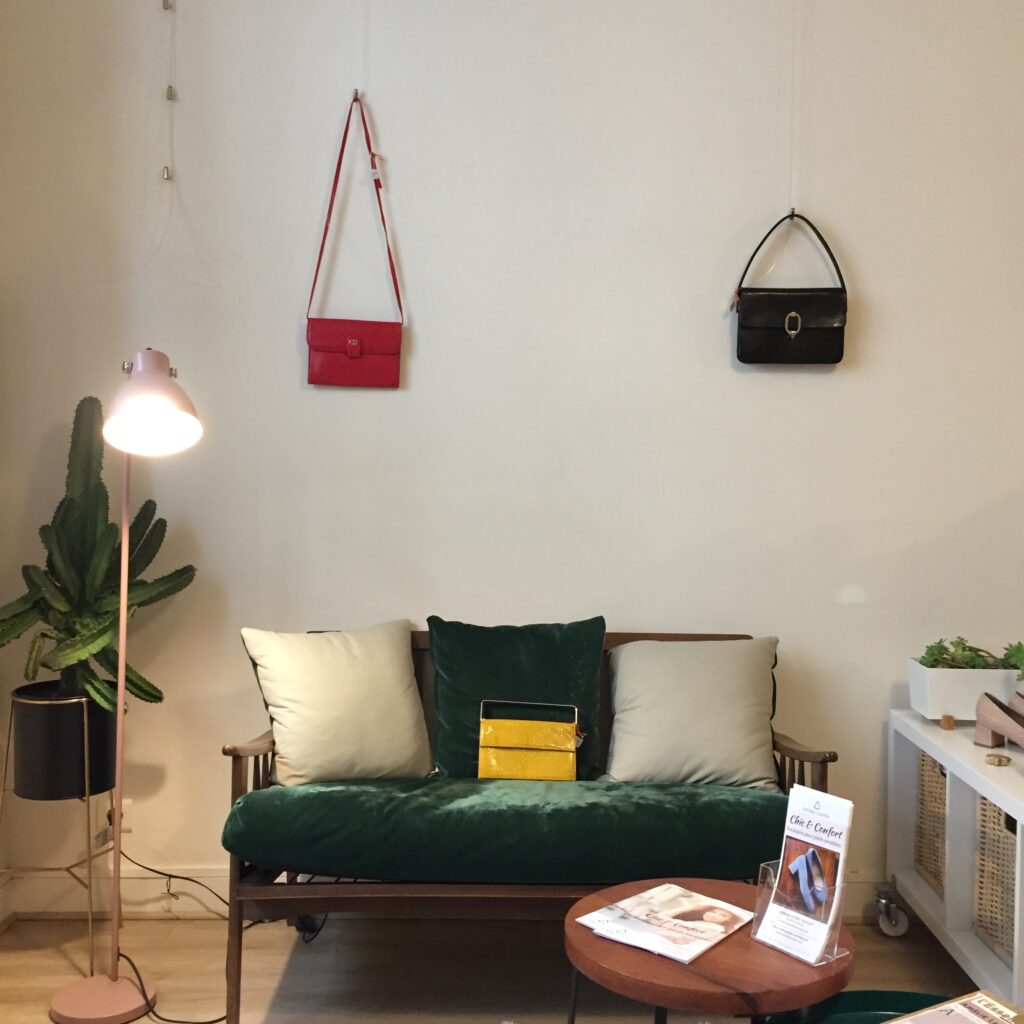 dans un showroom, des sacs à main vintage accrochés au mur et posé sur un canapé
